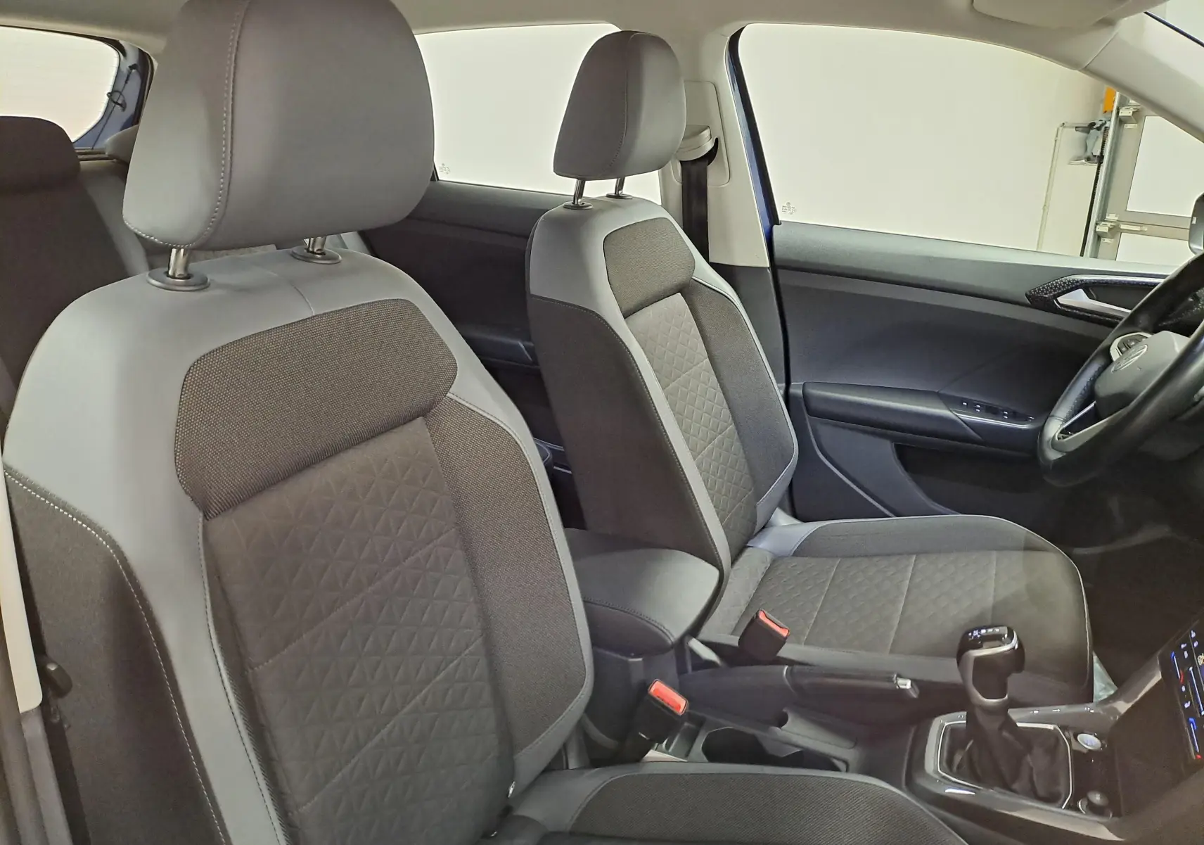 Vue intérieure des sièges avant gris et noir du Volkswagen T-Cross 2022, côté droit avec console centrale et levier de vitesse.