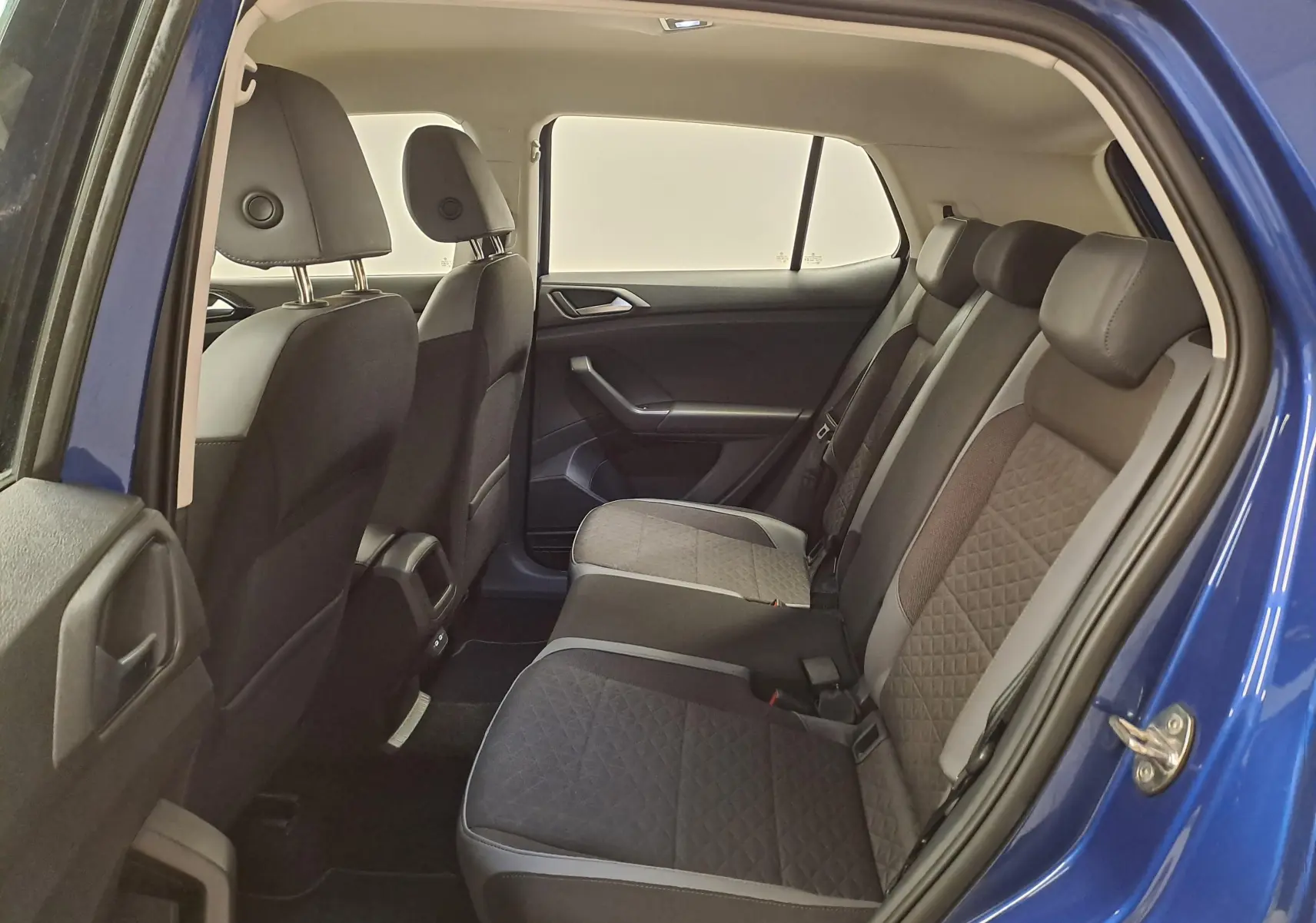 Vue intérieure côté droit des sièges arrière du Volkswagen T-Cross bleu récif, montrant la sellerie tissu bicolore.