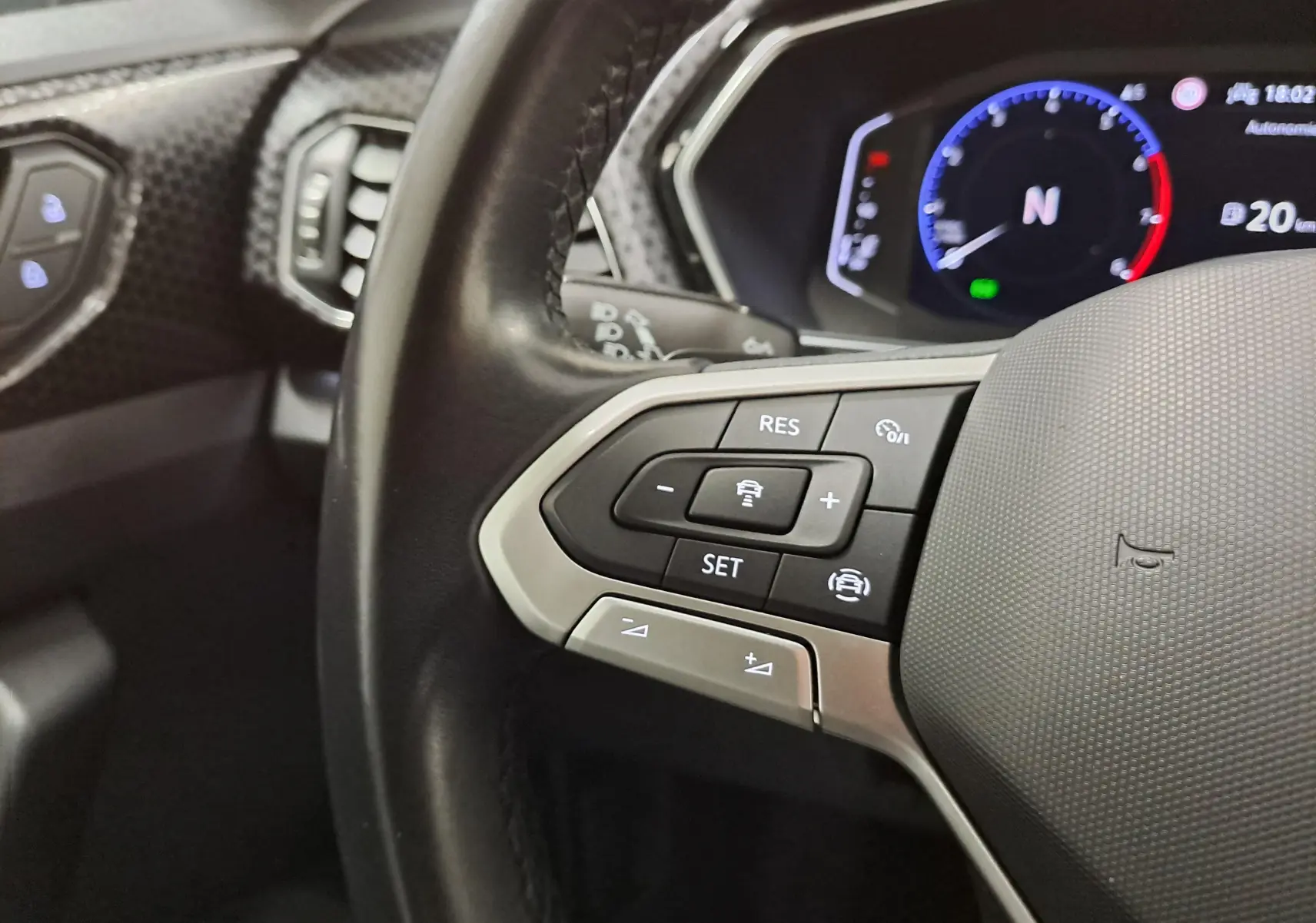 Gros plan sur le volant côté gauche du Volkswagen T-Cross 2022 avec commandes de régulateur et tableau de bord numérique.