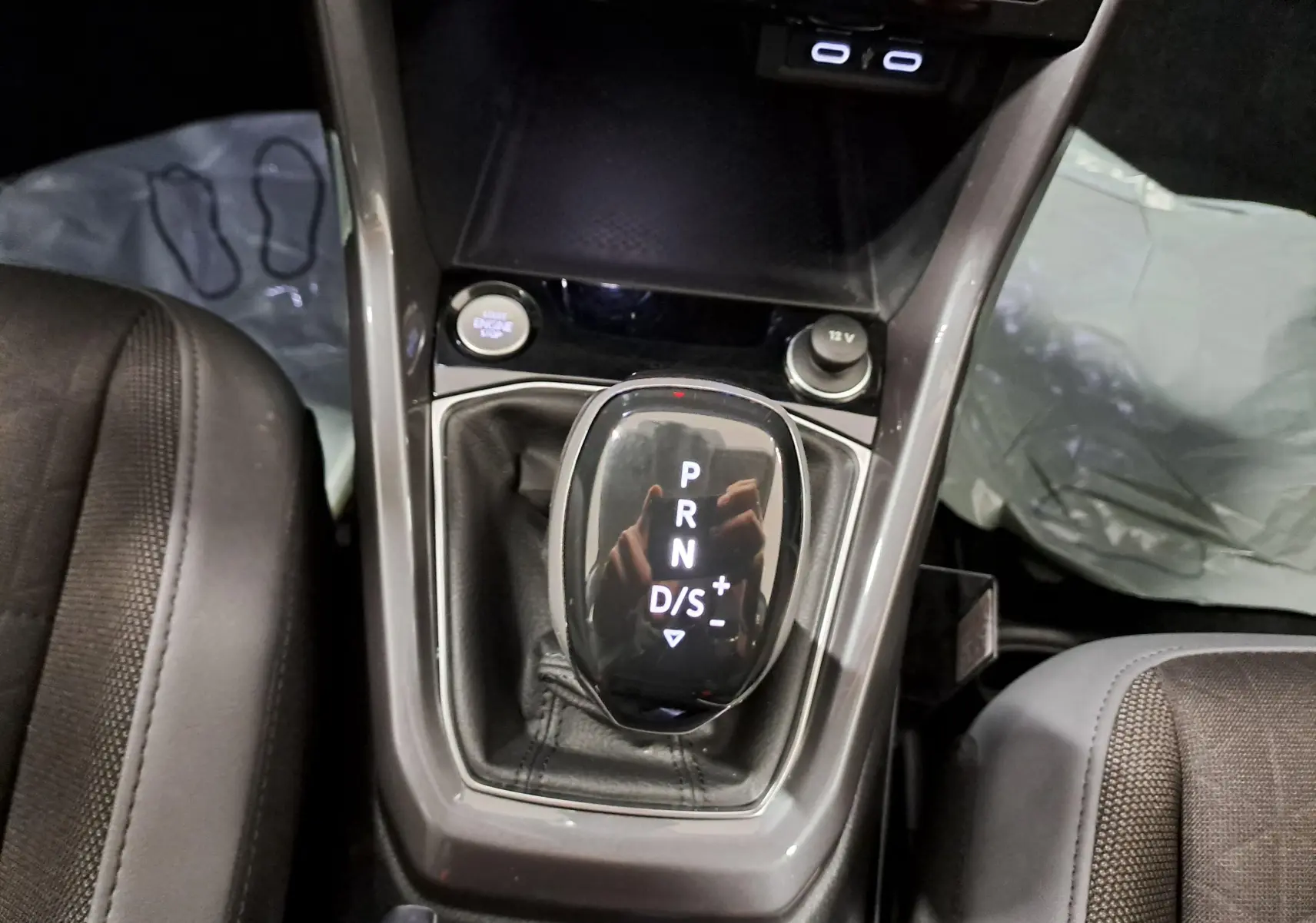 Vue rapprochée de la console centrale du Volkswagen T-Cross bleu récif, avec levier de vitesse automatique et bouton Start/Stop.