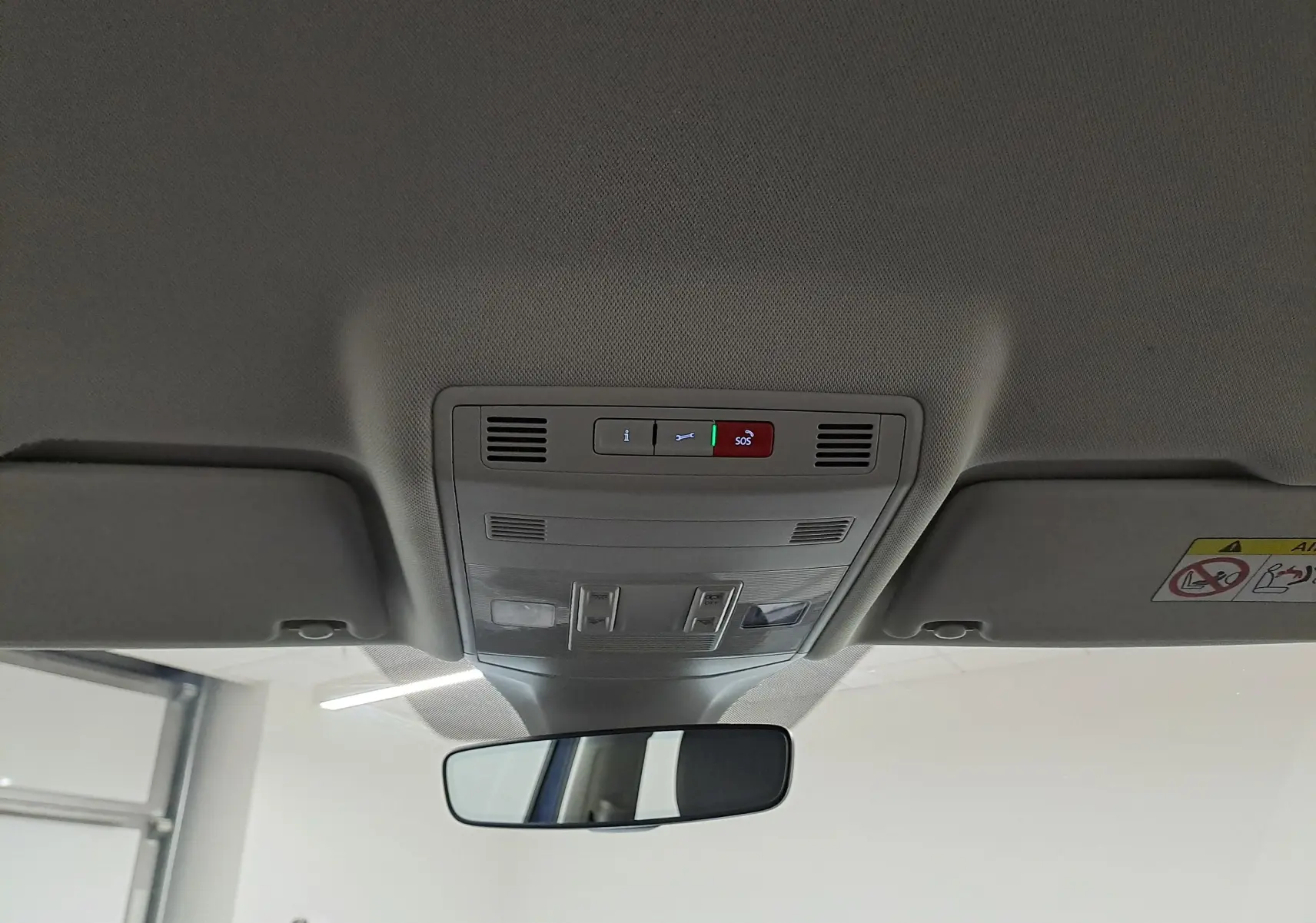 Vue intérieure du plafond avant du Volkswagen T-Cross bleu récif, montrant les commandes d'éclairage et le rétroviseur central.