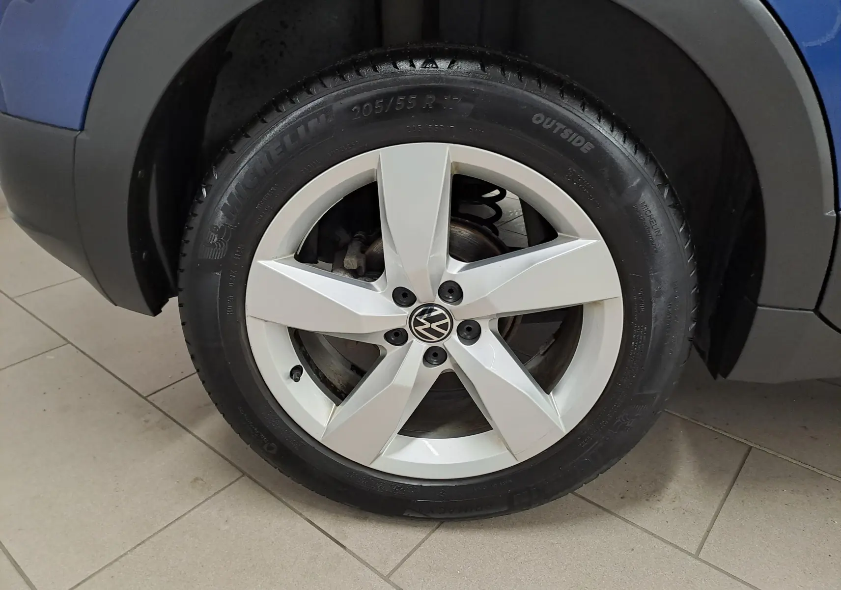Gros plan sur la roue avant gauche du Volkswagen T-Cross bleu Récif, jante alliage cinq branches argentées.