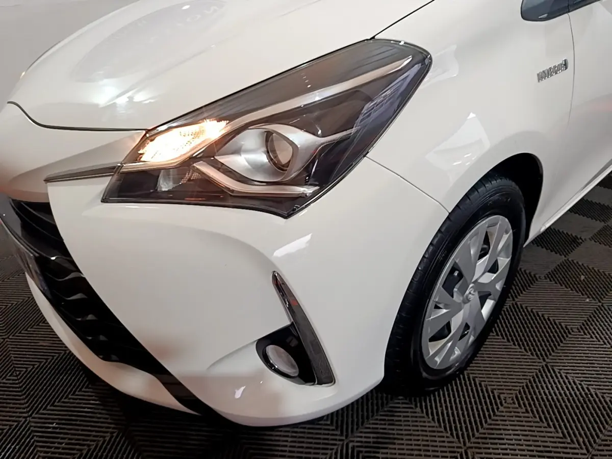 Gros plan sur l'avant droit blanc d'une Toyota Yaris 2019 avec phare allumé et antibrouillard visible.