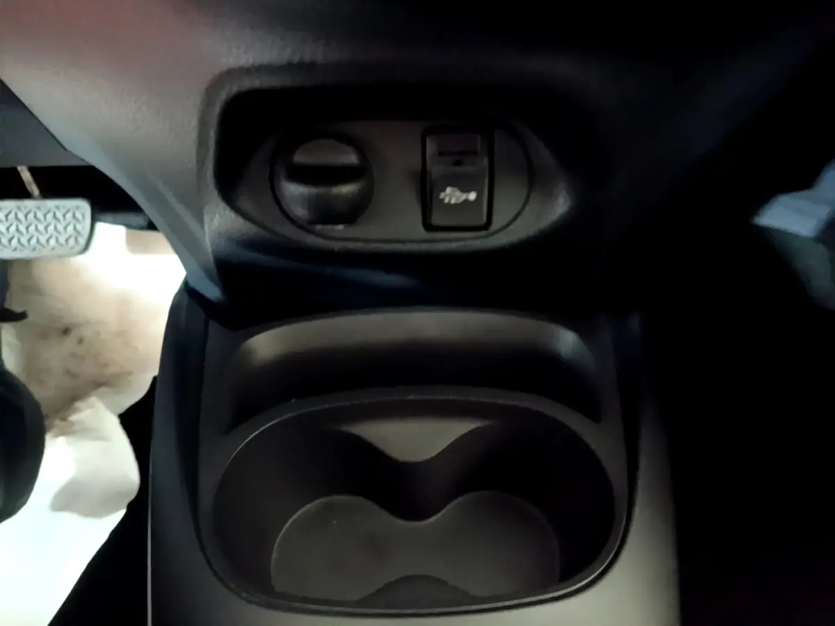 Gros plan sur le compartiment porte-gobelets et commande d'ouverture du capot dans l'habitacle d'une Toyota Yaris blanche 2019.