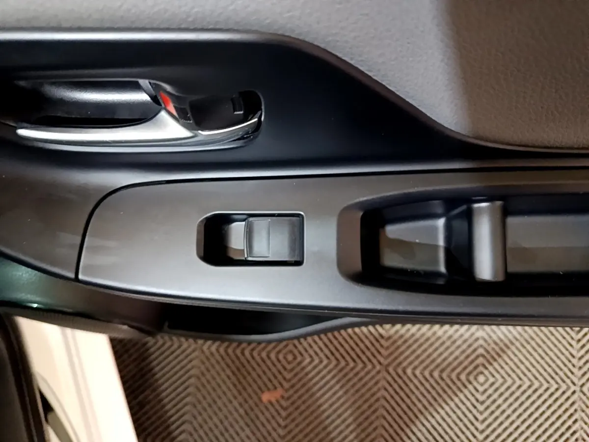 Vue rapprochée de la poignée intérieure et des commandes de la porte côté conducteur d'une Toyota Yaris blanche.