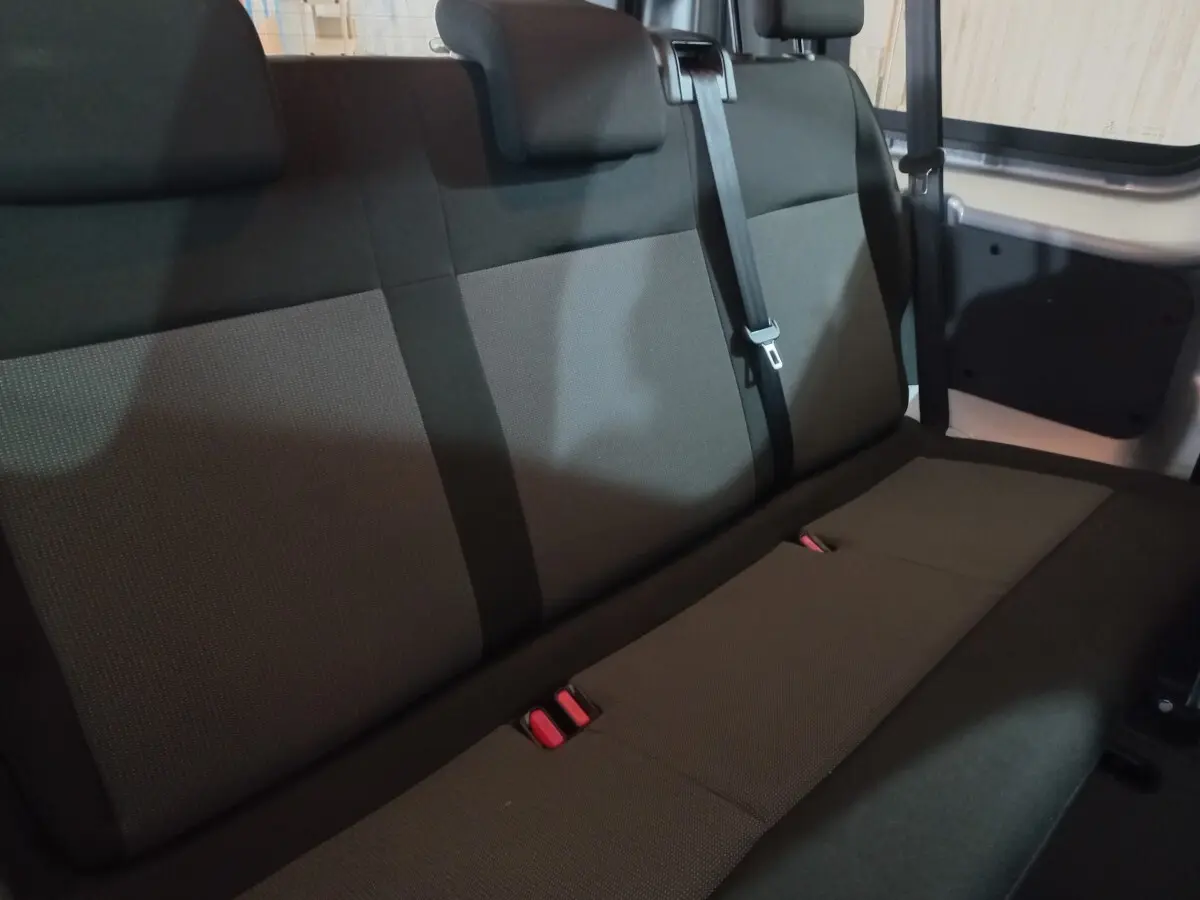 Vue intérieure de la banquette arrière grise du Peugeot Traveller 1.5 BlueHDi 120, avec ceintures et appuie-têtes.