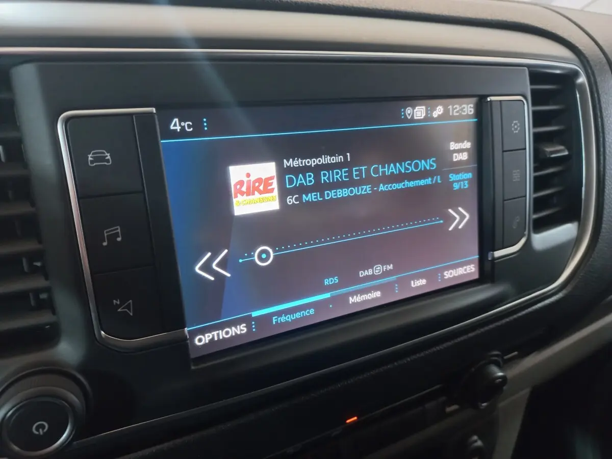 Gros plan sur l'écran tactile central du Peugeot Traveller 2021 affichant une station radio numérique.