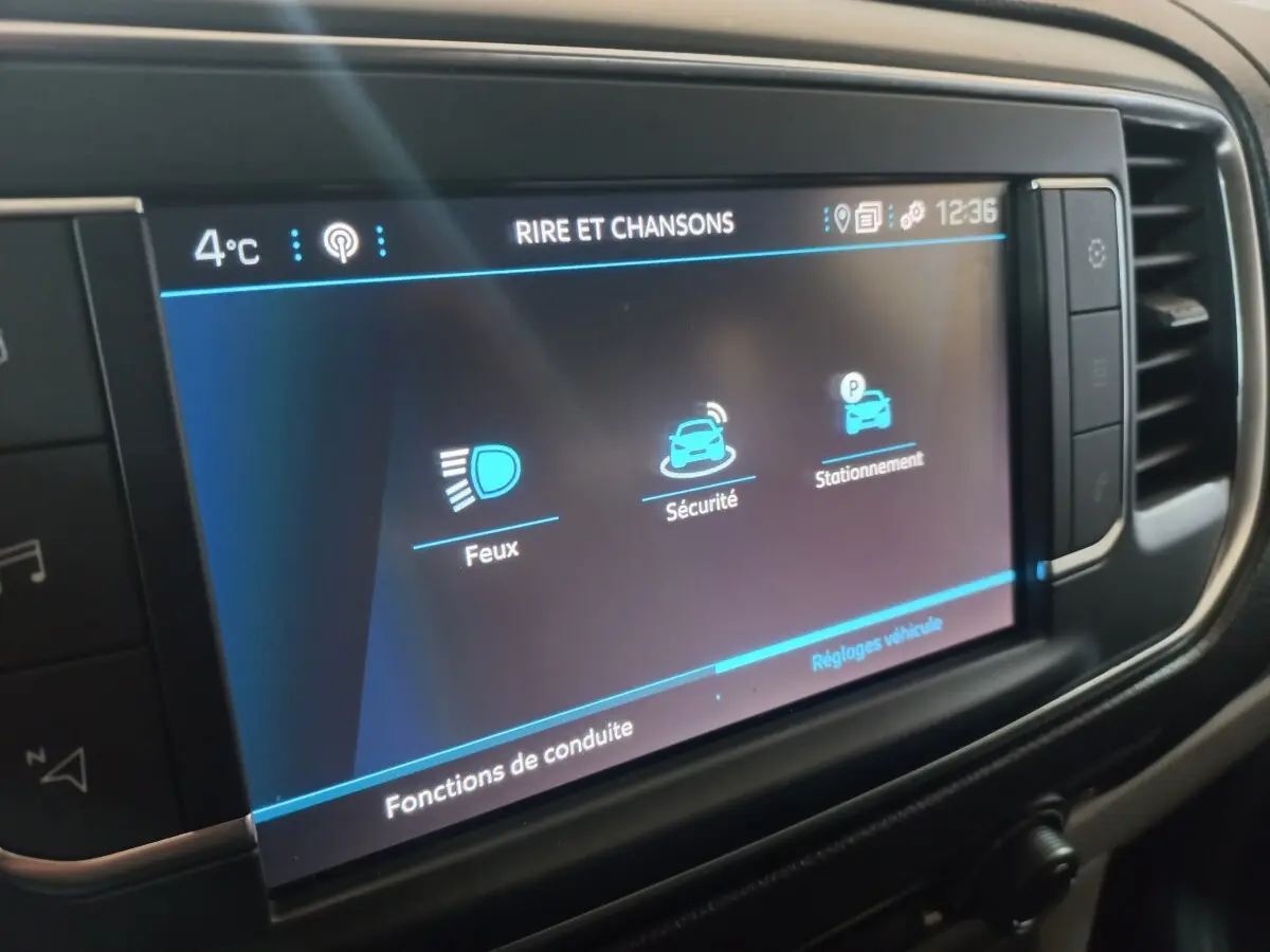 Écran tactile central du Peugeot Traveller gris clair, affichant les réglages de conduite et sécurité.