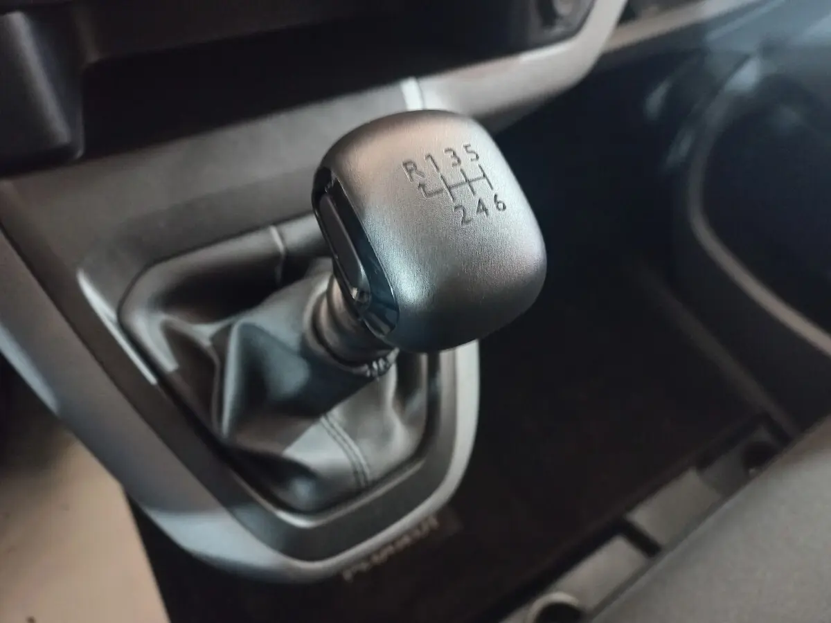 Gros plan sur le levier de vitesses manuel noir du Peugeot Traveller 1.5 BlueHDi 120, intérieur sombre.
