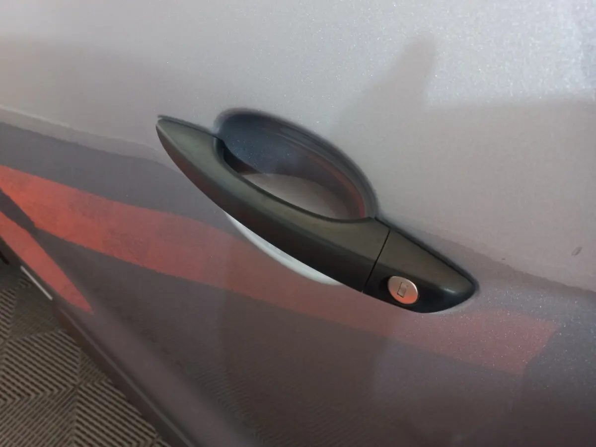 Poignée de porte noire sur la porte gris clair d’un Peugeot Traveller, vue en gros plan latéral.