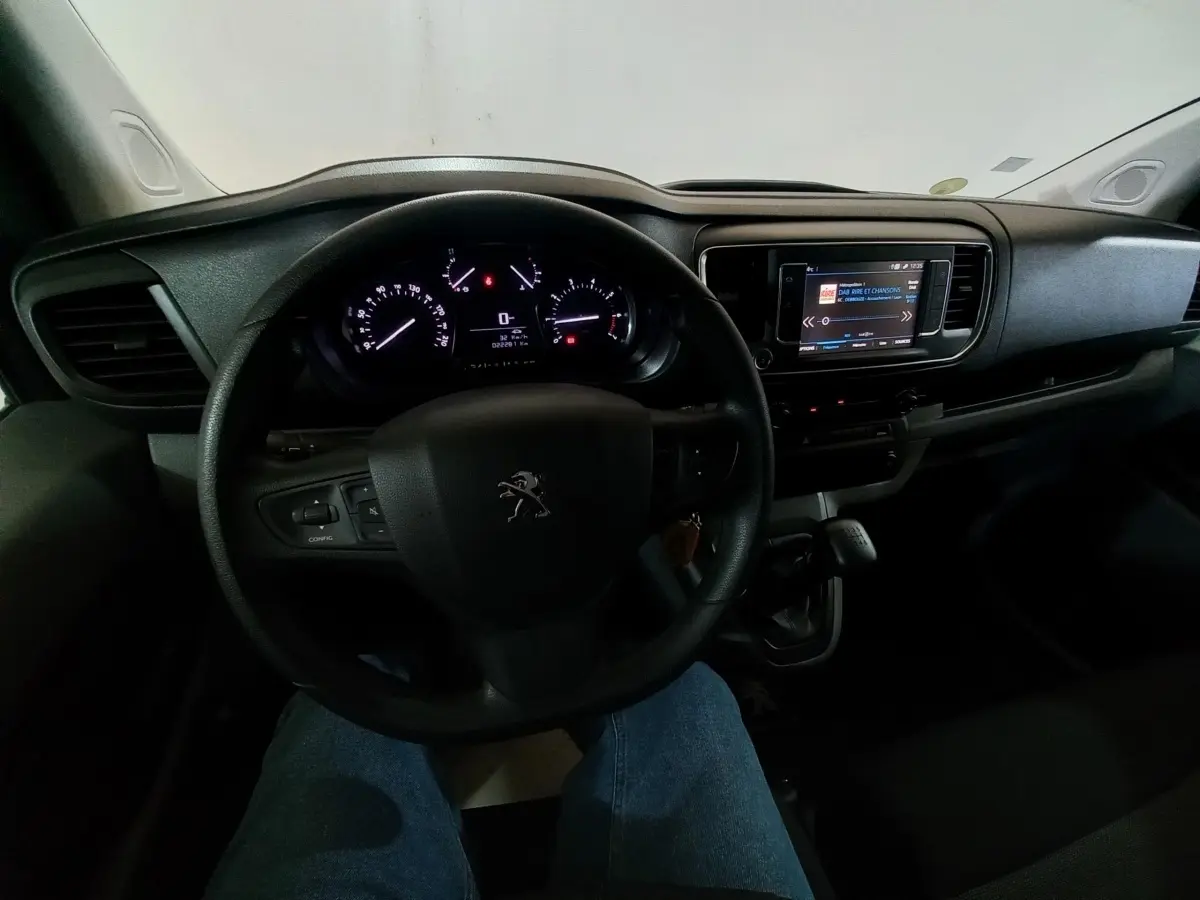 Vue intérieure centrée sur le volant et le tableau de bord du Peugeot Traveller 1.5 BlueHDi 120, avec écran tactile allumé.
