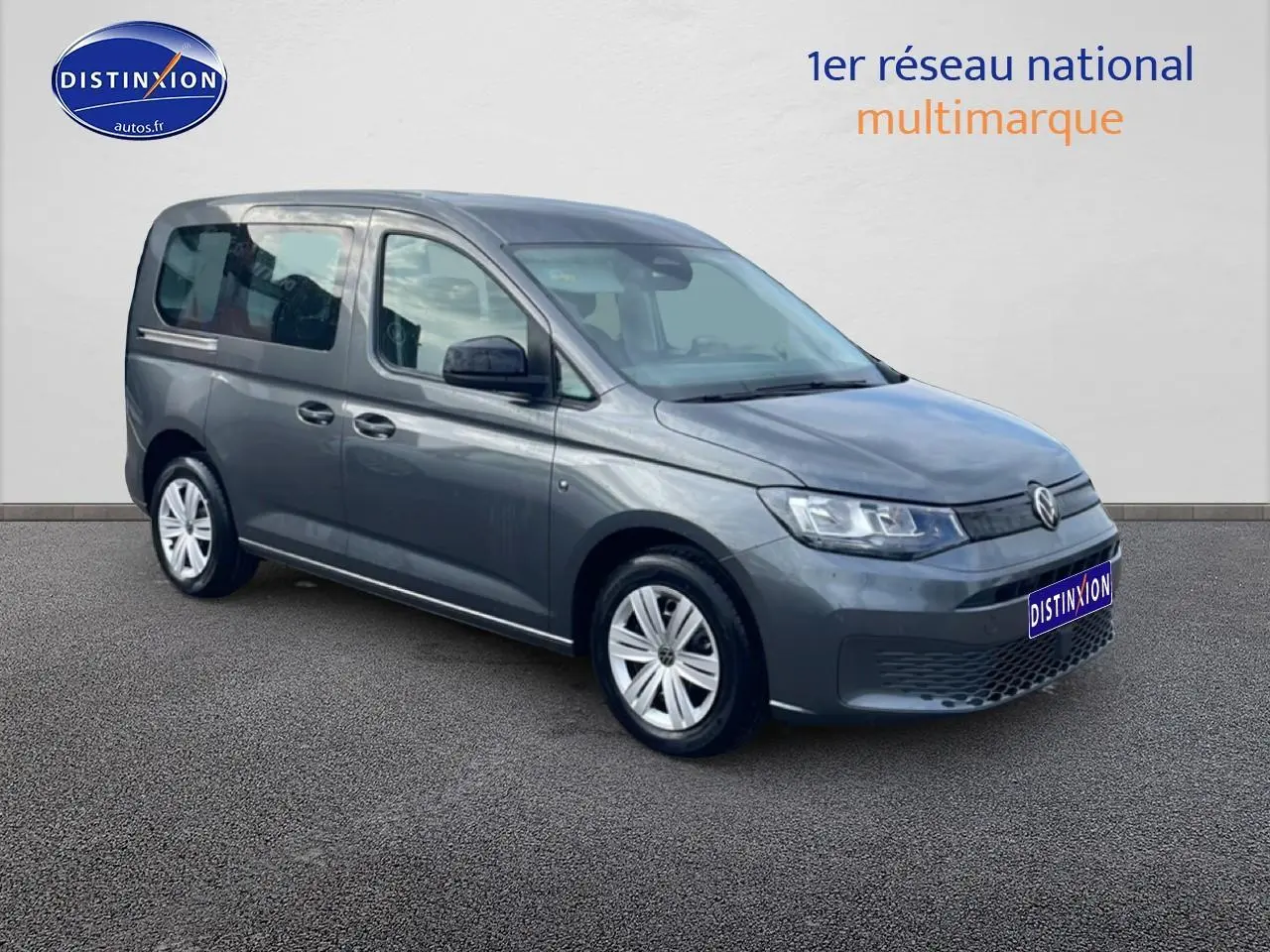 Volkswagen Caddy gris indien en 3/4 avant droit, avec vitres teintées et jantes alliage simples.