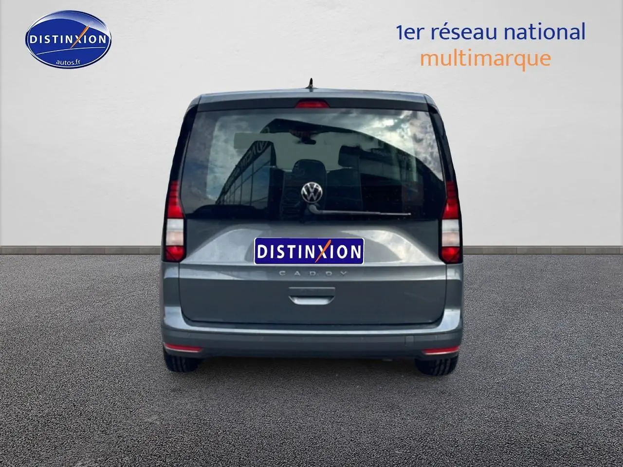 Vue arrière d'un Volkswagen Caddy gris indien 2025 avec vitres teintées et logo VW visible.