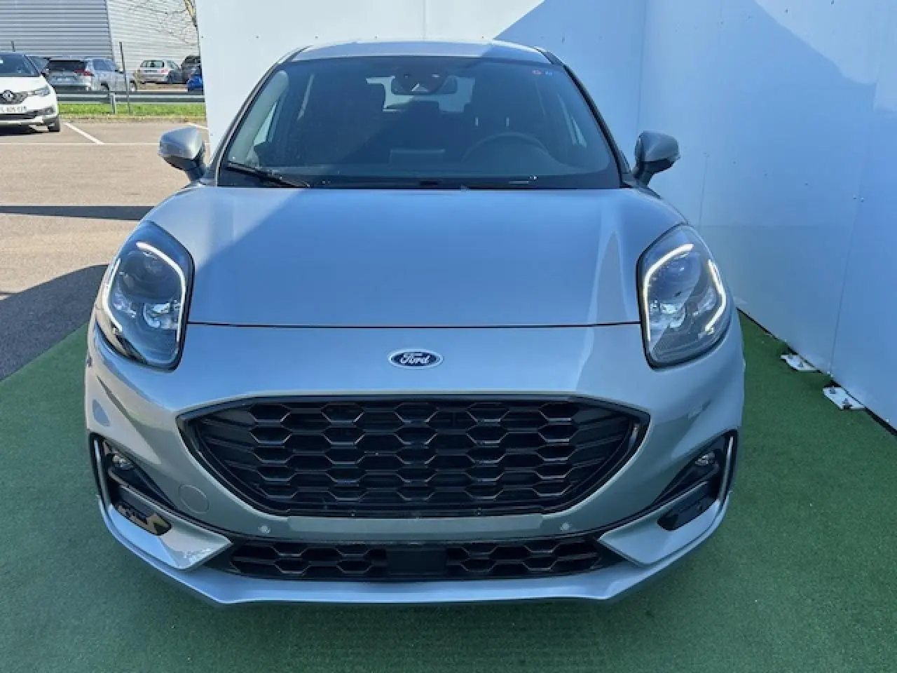 Vue avant d'un Ford Puma gris Magnetic 2023 avec calandre noire hexagonale et phares LED allumés.