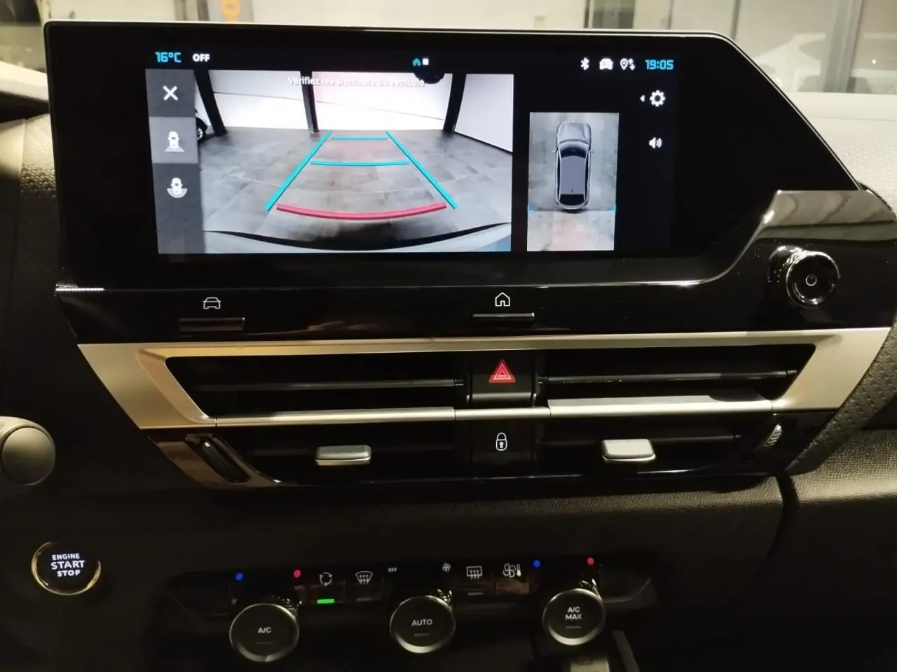 Vue rapprochée de l’écran central tactile affichant la caméra de recul et les commandes de climatisation sur tableau de bord noir.