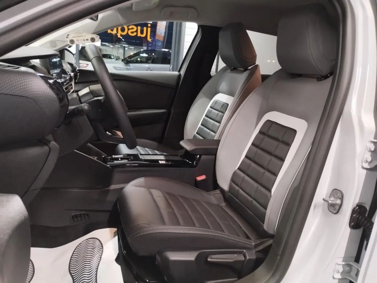 Vue intérieure côté conducteur de la Citroën C4 2025 blanche, sièges Advanced Comfort bicolores noir et gris.