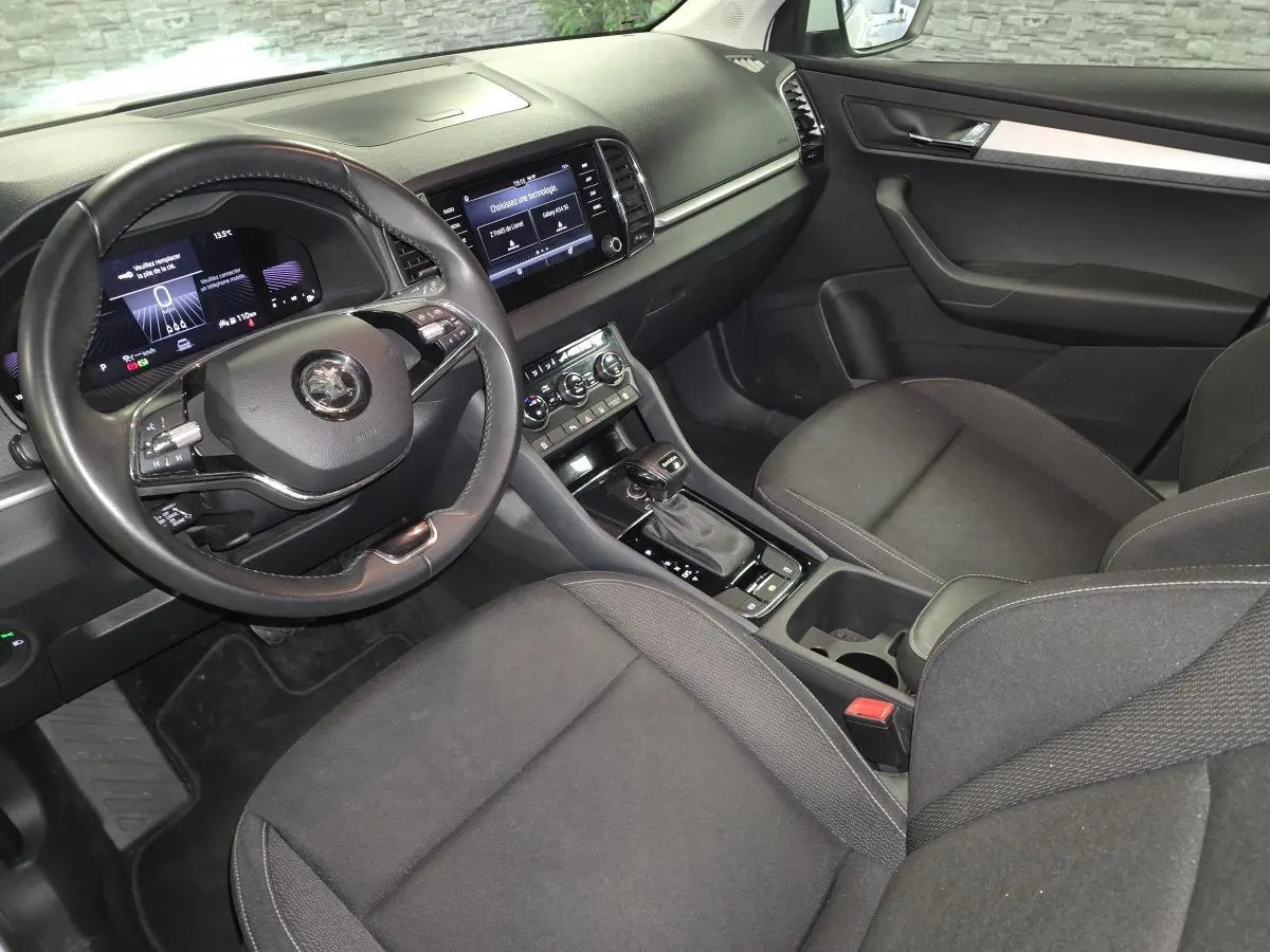 Intérieur avant droit de la Skoda Karoq 2023, tableau de bord noir avec écran tactile et volant cuir multifonctions.