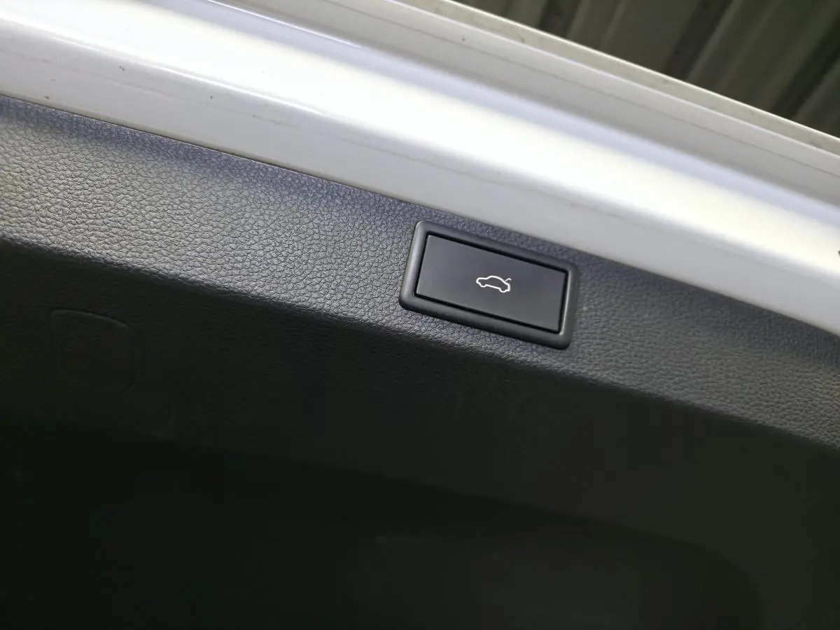 Bouton d'ouverture électrique du hayon sur la garniture intérieure noire d'un Skoda Karoq blanc.