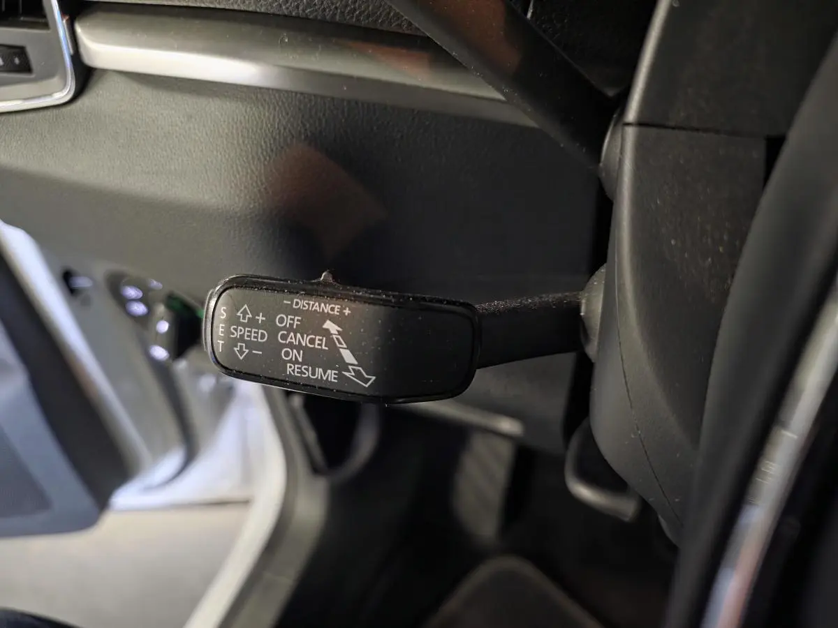 Gros plan sur la commande de régulateur de vitesse adaptatif dans l'habitacle du Skoda Karoq blanc 2023.