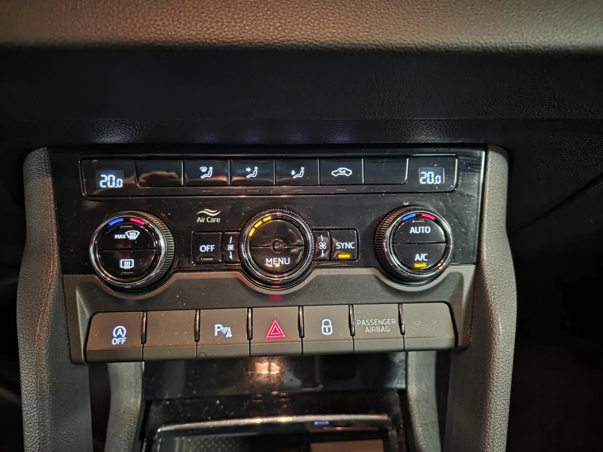 Vue rapprochée de la console centrale noire du Skoda Karoq 2023 avec commandes climatisation bi-zone et boutons fonctionnels.