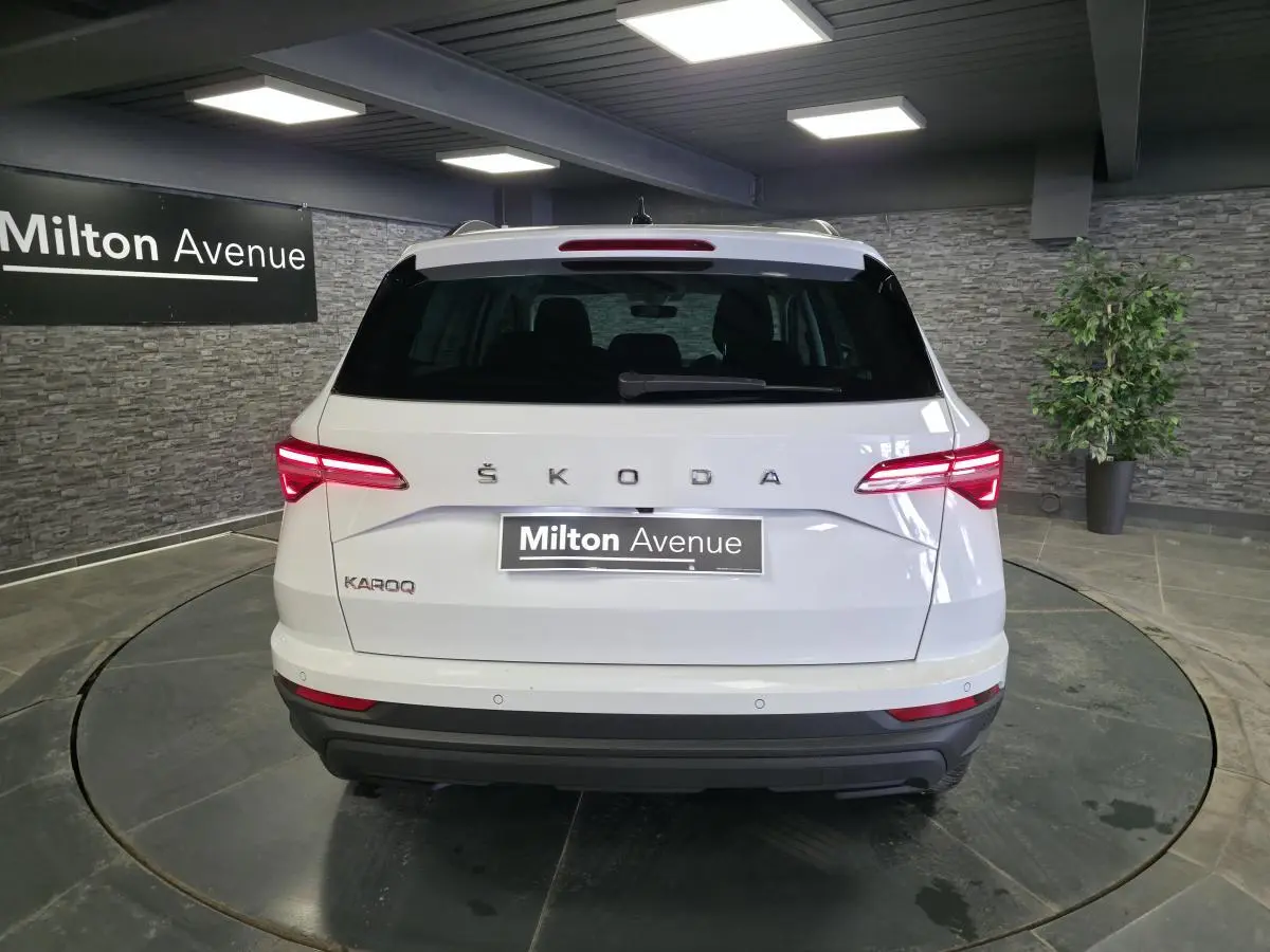 Vue arrière d'un Skoda Karoq blanc 2023 avec feux arrière LED allumés dans un showroom intérieur.