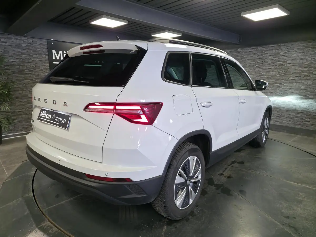 Vue 3/4 arrière droite d’un Skoda Karoq blanc 2023 avec feux arrière LED et jantes alliage 17 pouces.