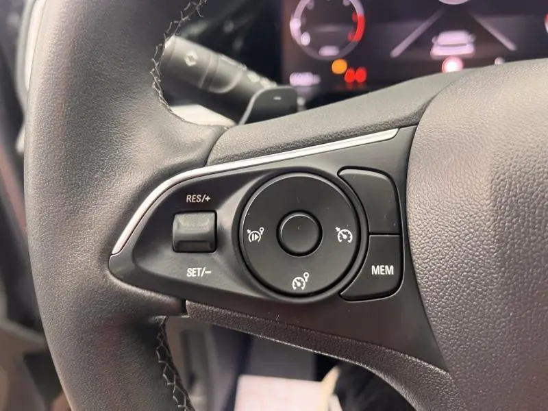 Gros plan sur les commandes de régulateur de vitesse au volant cuir noir de l’Opel Grandland 2022.