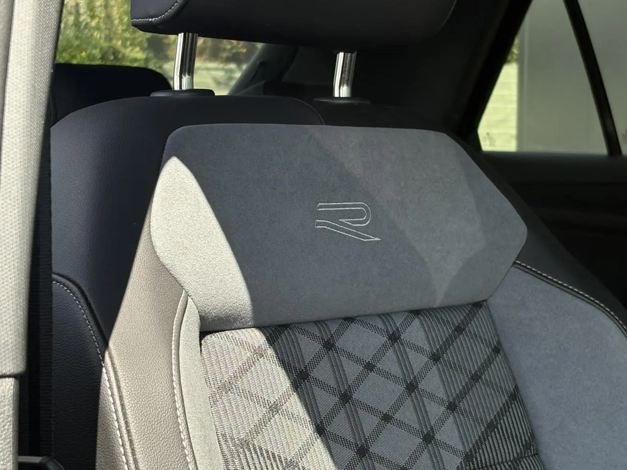 Gros plan sur l’appui-tête avant en cuir et alcantara gris avec logo R-Line brodé, intérieur Volkswagen T-Roc noir.