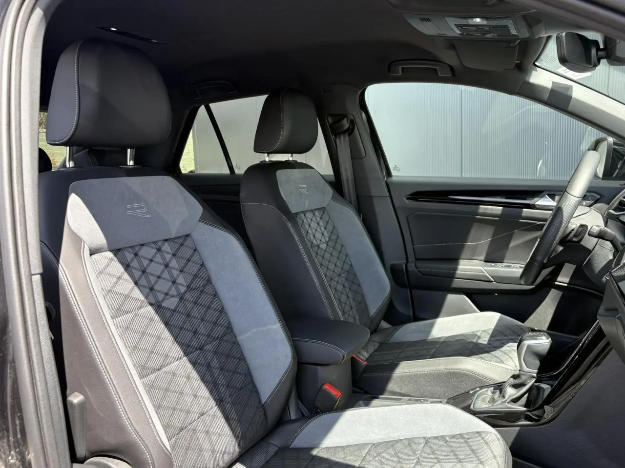 Vue intérieure côté droit des sièges avant en cuir et alcantara gris avec logo R-Line sur un Volkswagen T-Roc noir.