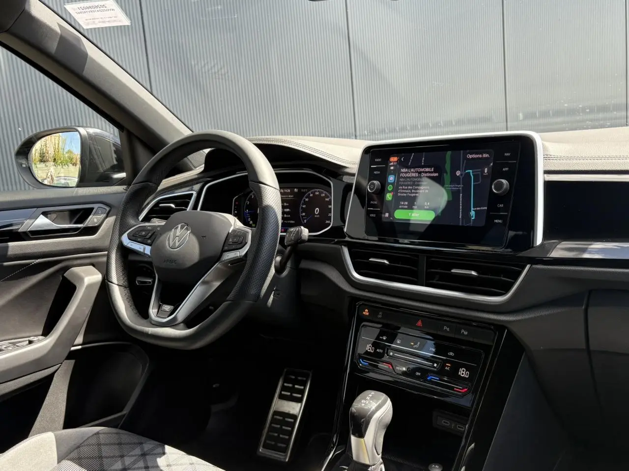 Intérieur du Volkswagen T-Roc 1.5 TSI 2025 vu côté conducteur, volant cuir R-Line et écran tactile central allumé.