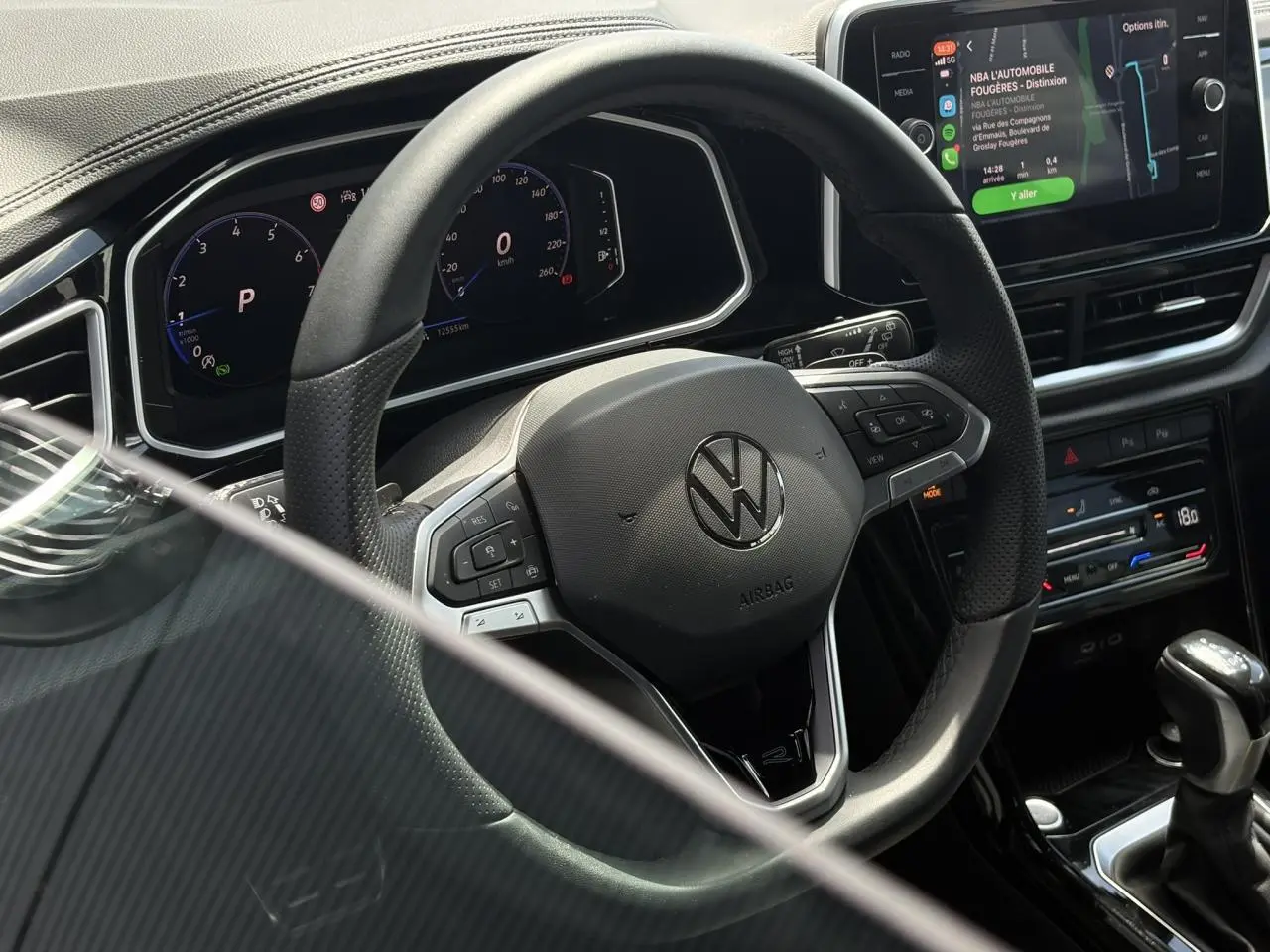 Vue rapprochée du volant cuir noir avec logo Volkswagen et tableau de bord digital du Volkswagen T-Roc 1.5 TSI R-Line 2025.