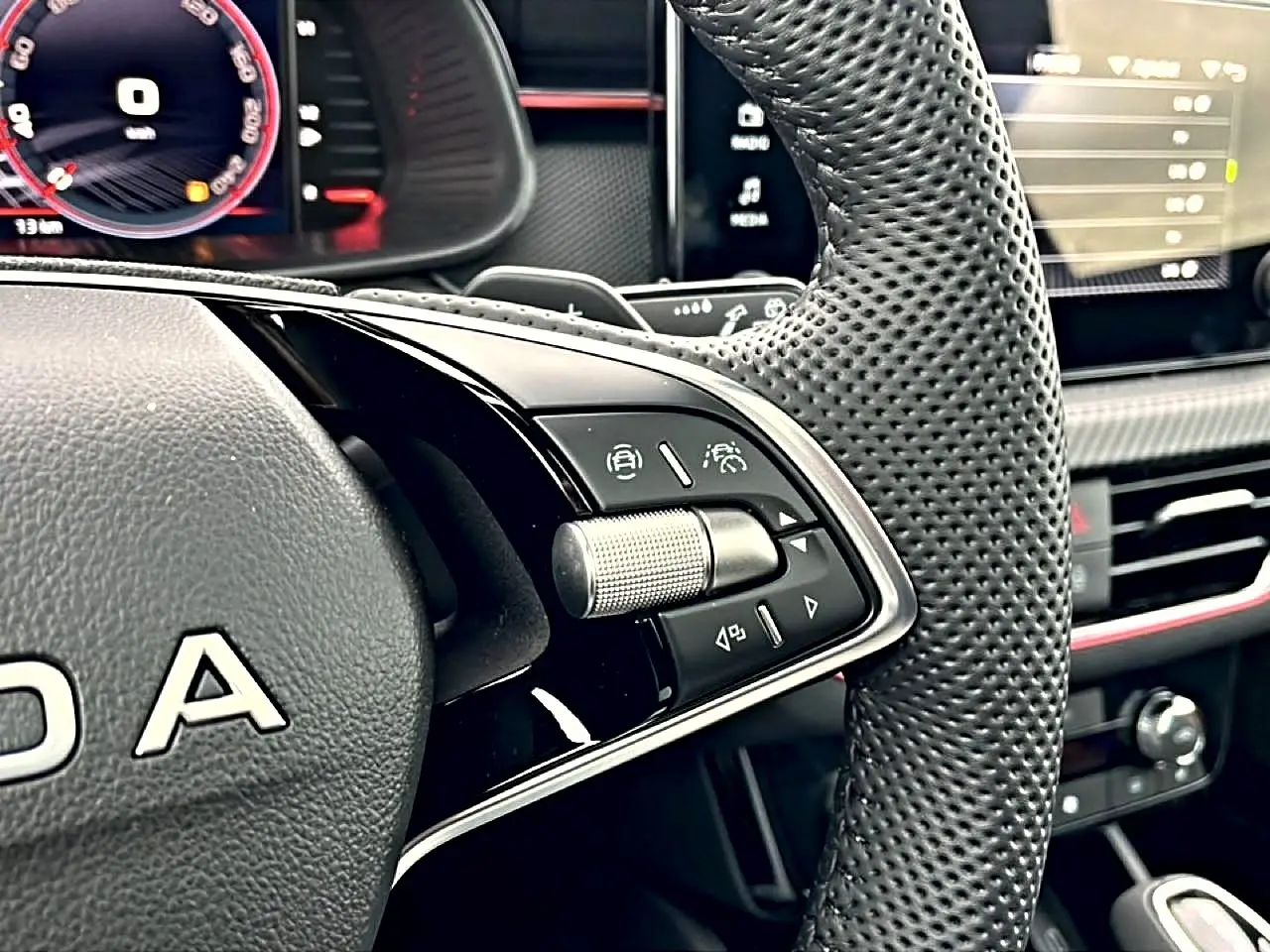 Gros plan sur le volant sport perforé noir du Skoda Kamiq 2026 avec commandes multifonctions et tableau de bord numérique.