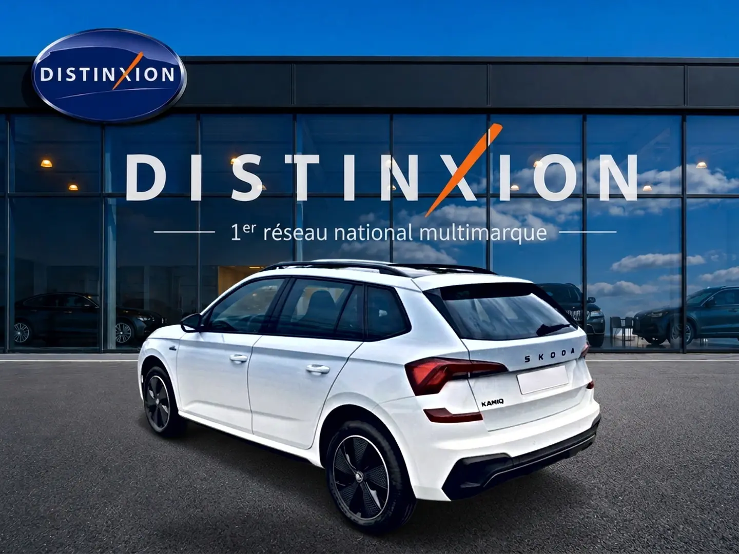 Vue 3/4 arrière droite d'un Skoda Kamiq blanc nacré avec jantes noires, garé devant une vitrine Distinxion.