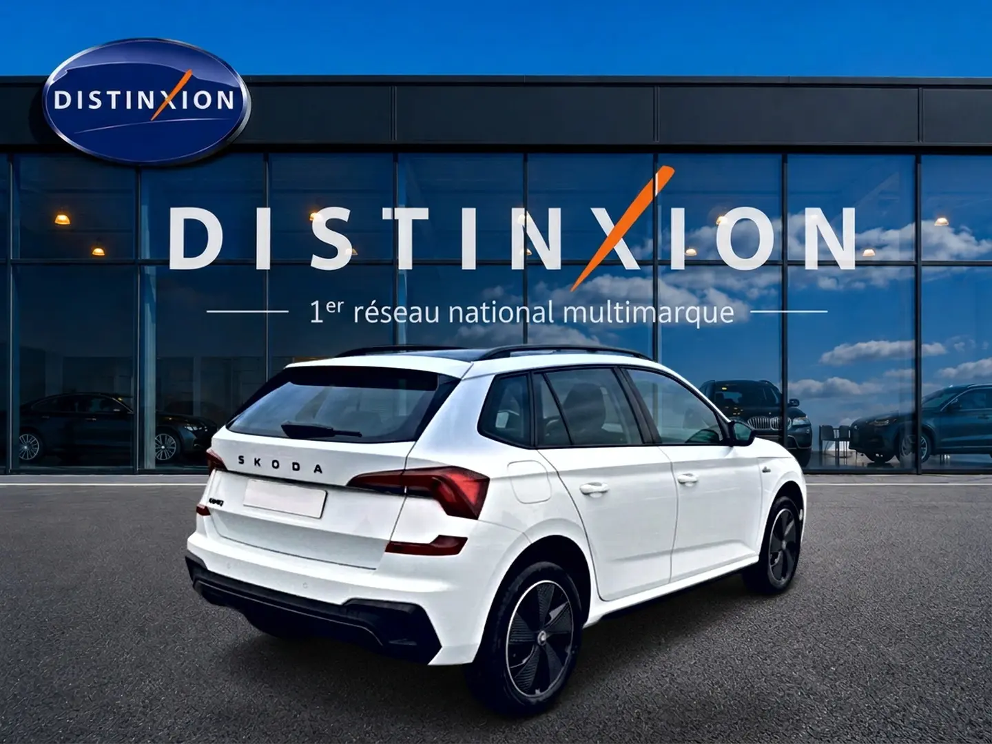 Vue 3/4 arrière droite d'un Skoda Kamiq blanc nacré avec jantes noires, devant une vitrine Distinxion.