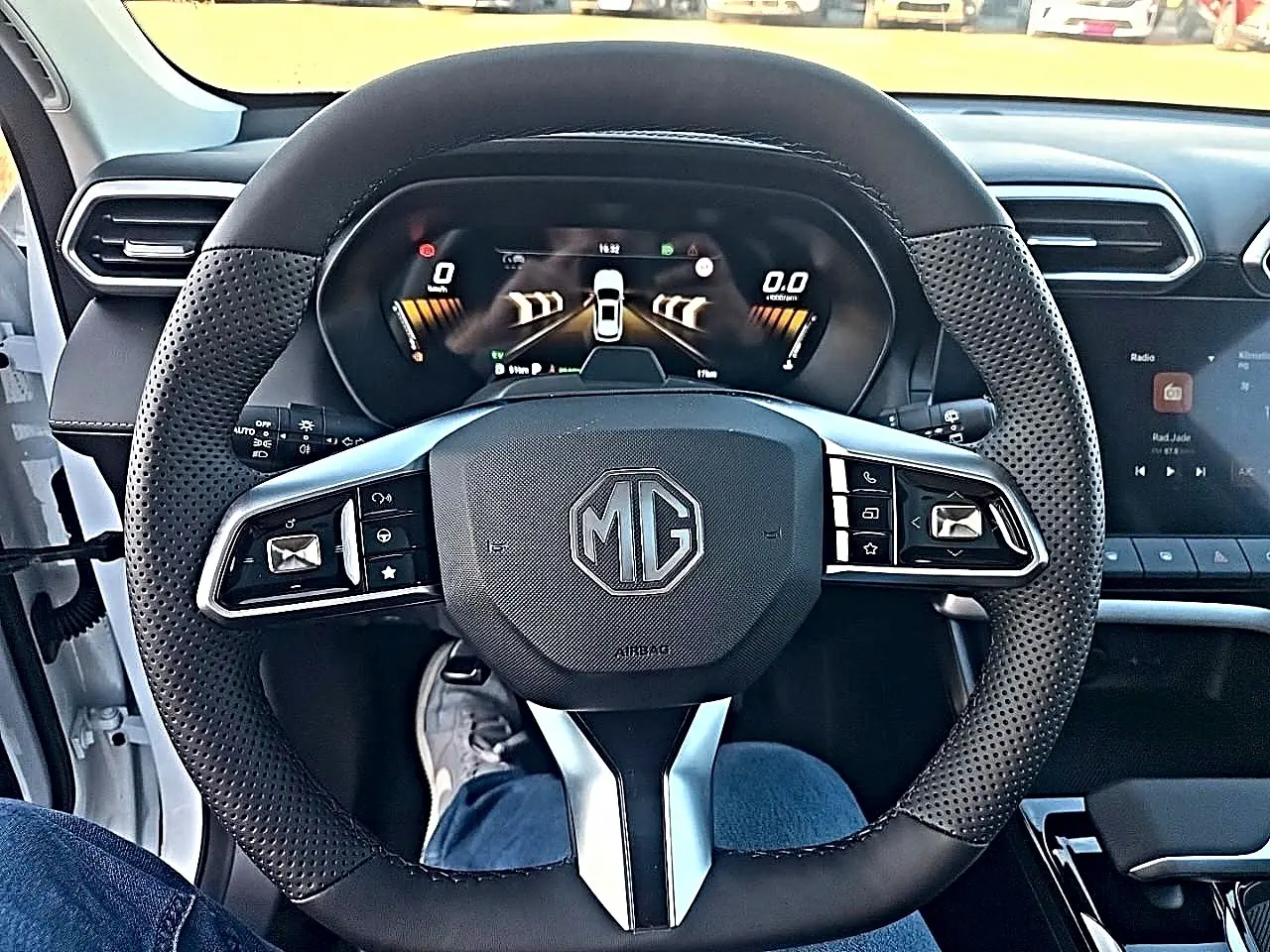 Vue intérieure centrée sur le volant multifonction noir perforé du MG ZS 1.5 hybrid 197 luxury avec tableau de bord digital.