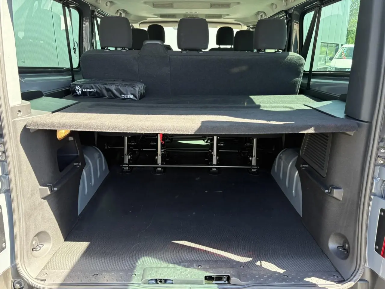 Vue arrière ouverte du Renault Trafic Fourgon Urban Grey montrant le coffre spacieux et la banquette arrière noire.