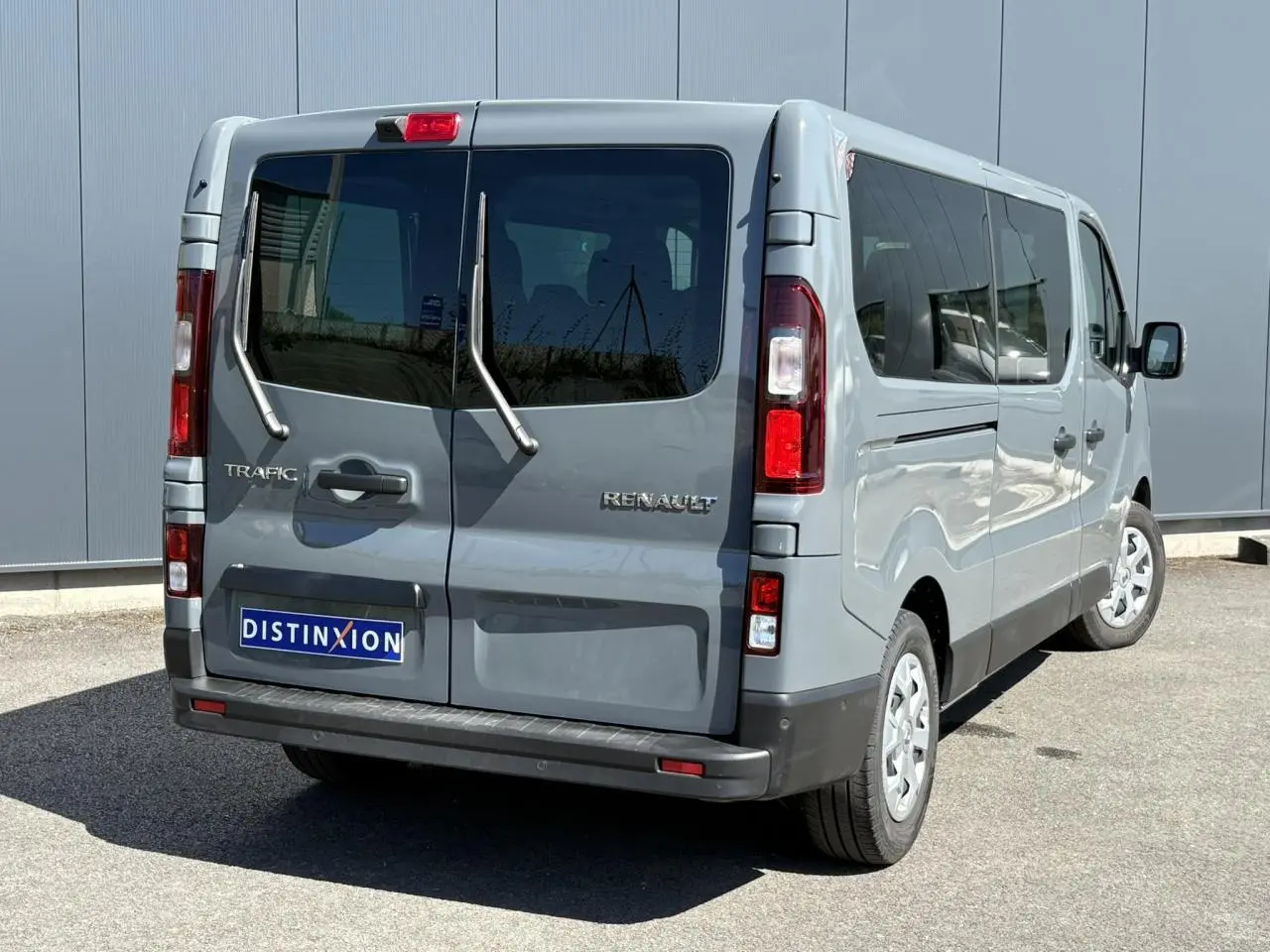 Vue 3/4 arrière droite du Renault Trafic Fourgon gris Urban avec portes arrière vitrées et essuie-glaces intégrés.