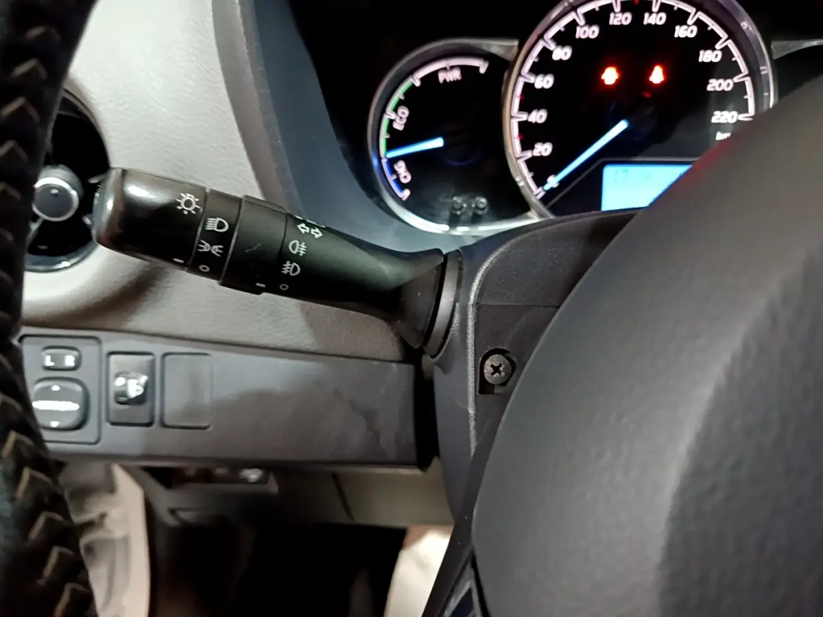 Gros plan sur le tableau de bord et commodo gauche de la Toyota Yaris hybride blanche de 2019, avec compte-tours et vitesse visibles.