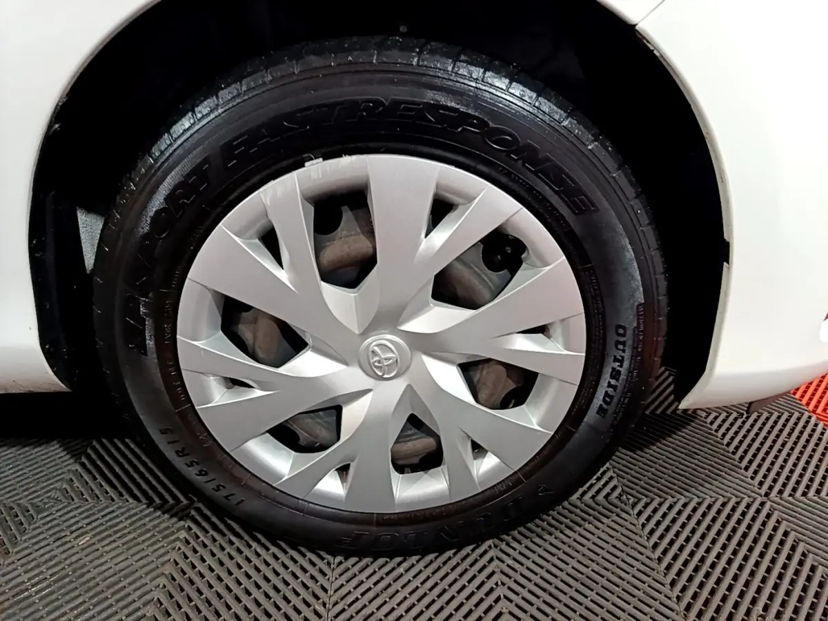 Gros plan sur la roue avant droite blanche d'une Toyota Yaris 1.5 VVT-I Hybrid avec enjoliveur argenté Toyota.