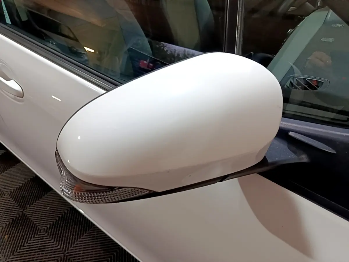 Rétroviseur côté gauche blanc de la Toyota Yaris hybride 2019, avec clignotant intégré visible en gros plan.