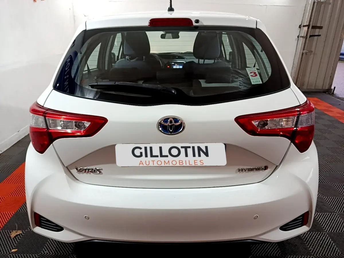 Vue arrière d'une Toyota Yaris hybride blanche 2019 avec feux arrière nets et logo Toyota centré.