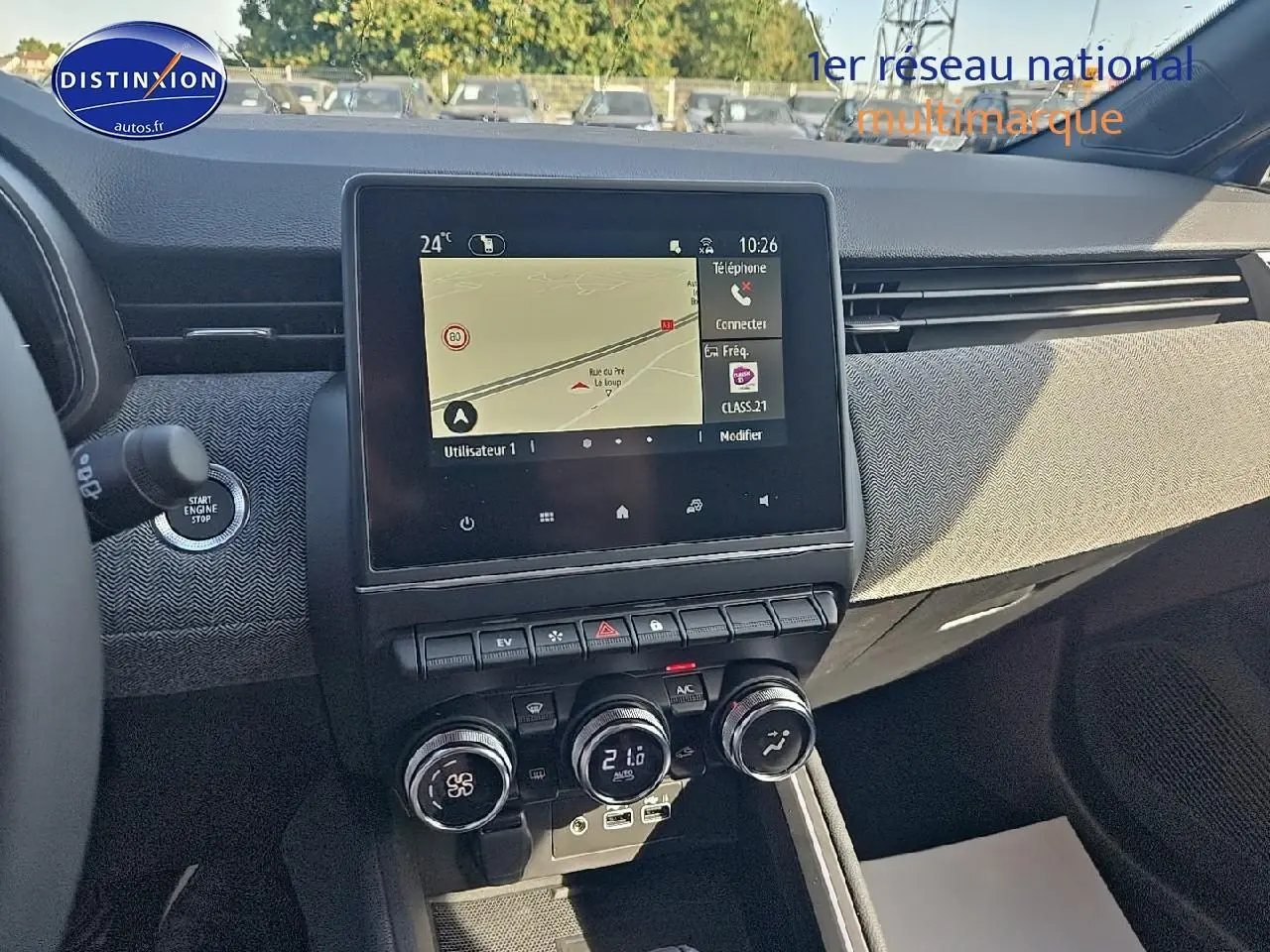 Vue intérieure du tableau de bord de la Renault Clio V 1.6 e-tech bleu iron, avec écran tactile et commandes de climatisation.