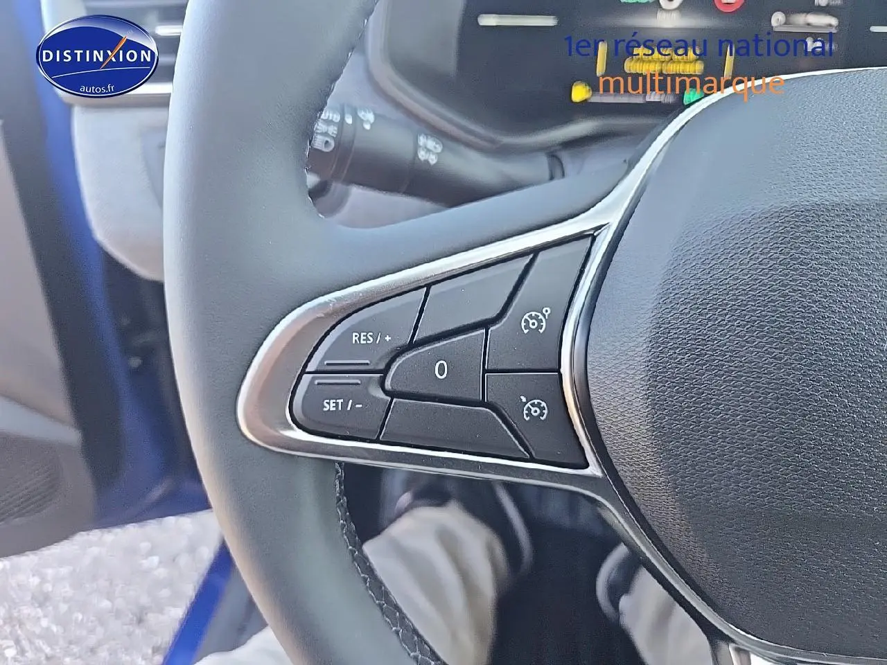 Gros plan sur les commandes de régulateur au volant d'une Renault Clio V bleu iron, côté gauche visible.