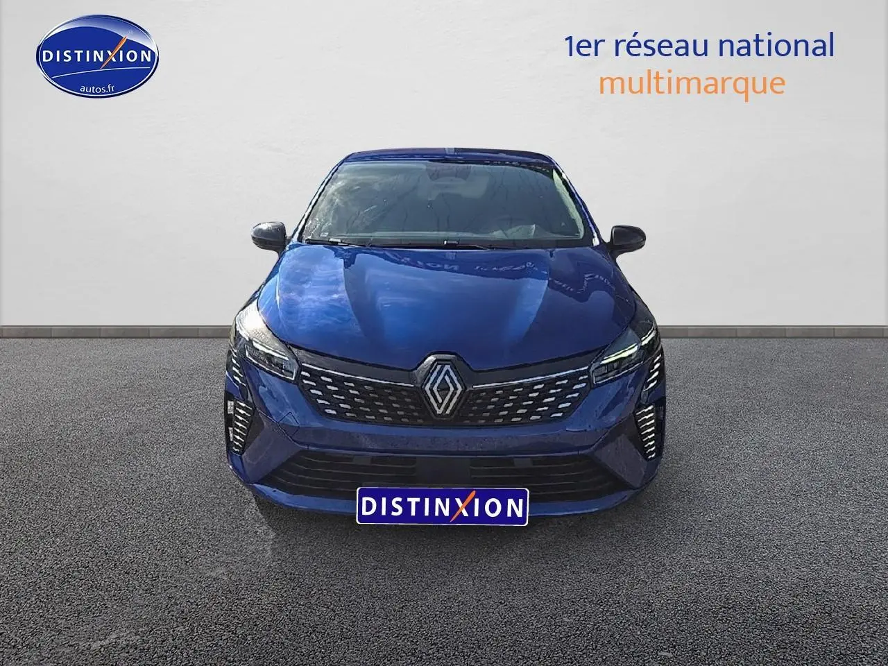 Vue frontale d'une Renault Clio V bleu iron avec calandre chromée et feux LED allumés.