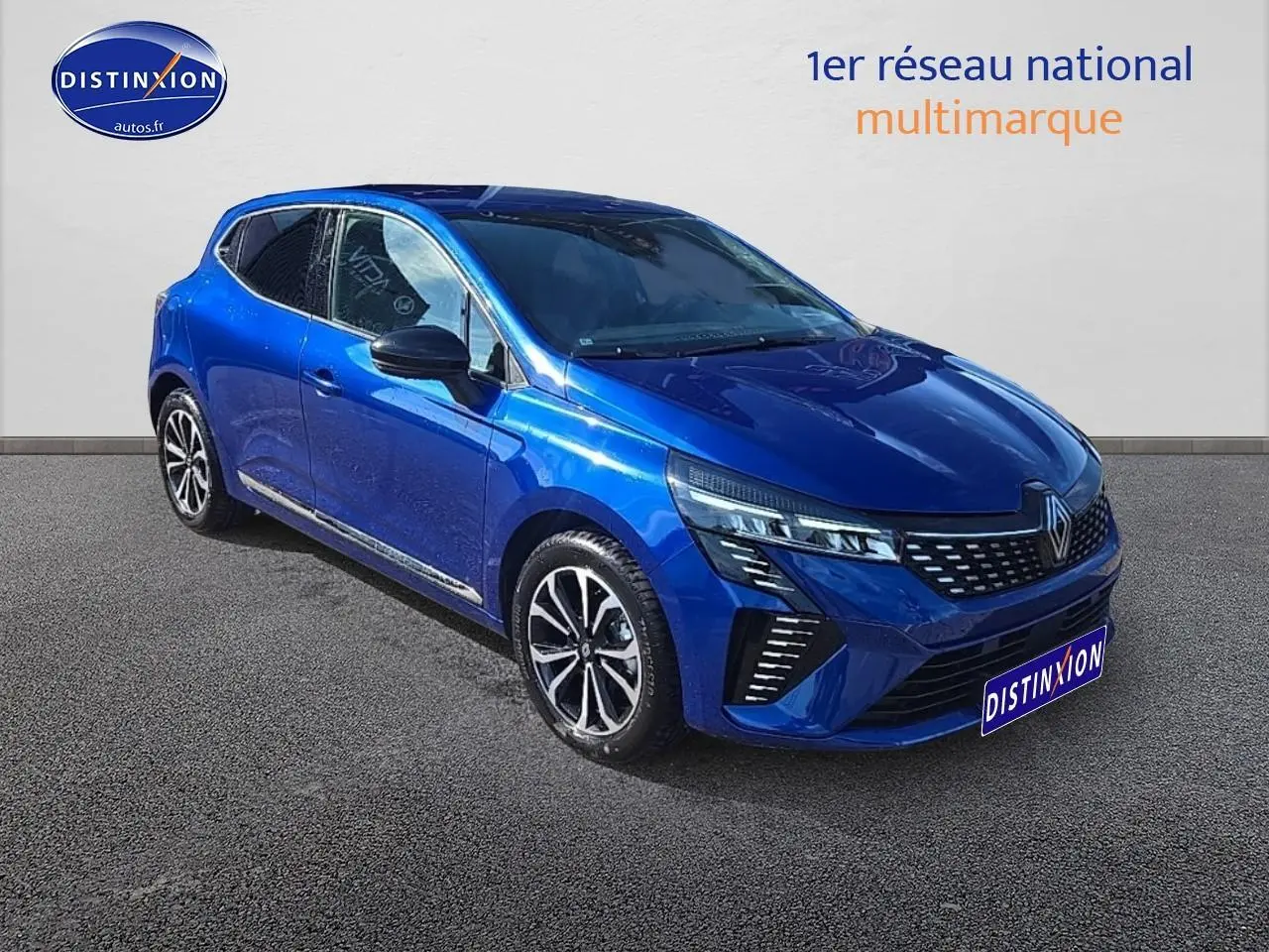 Renault Clio V 1.6 e-tech bleu iron vue 3/4 avant droit avec calandre chromée et jantes alu distinctives.