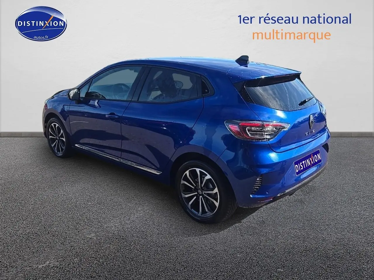 Vue 3/4 arrière droite d'une Renault Clio V bleu iron avec jantes alu et becquet arrière.