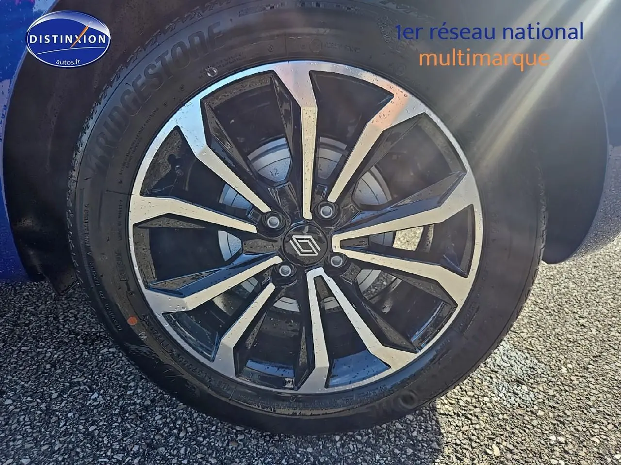 Gros plan sur la jante alu bicolore de la Renault Clio V Bleu Iron, avec logo Renault au centre.