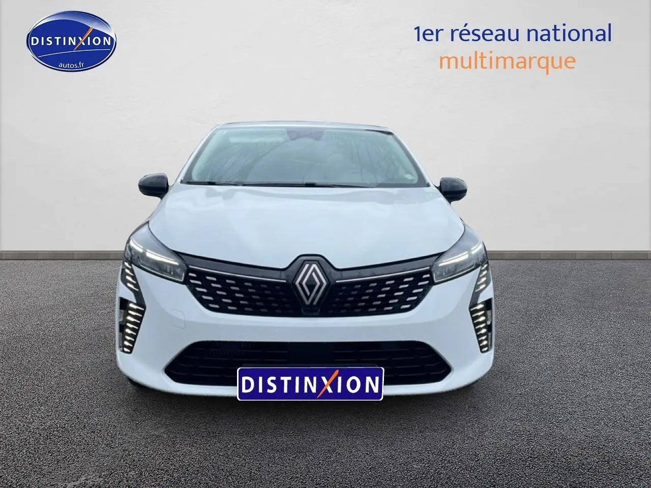 Vue avant d'une Renault Clio V blanche avec calandre noire et feux LED verticaux allumés.