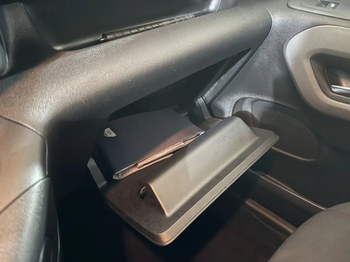 Vue intérieure du coffre à gants ouvert côté passager du Peugeot Rifter 2019, avec un carnet noir à l'intérieur.