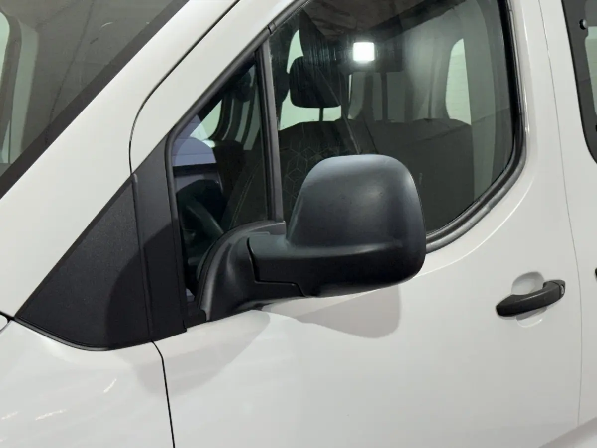 Vue rapprochée du côté gauche d’un Peugeot Rifter blanc 2019, mettant en valeur le rétroviseur noir et la porte avant.